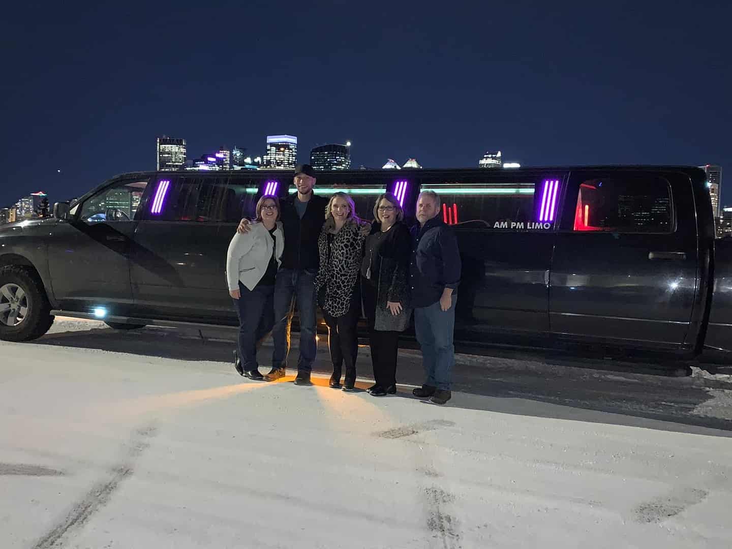 Small group smiling in front of Black Dodge Ram Limo
