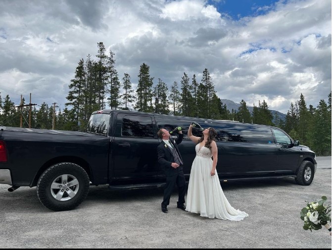 Bride and groom celebrating wedding day in front of limousine