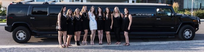 Ladies pose for photo in front of black Hummer Limousine