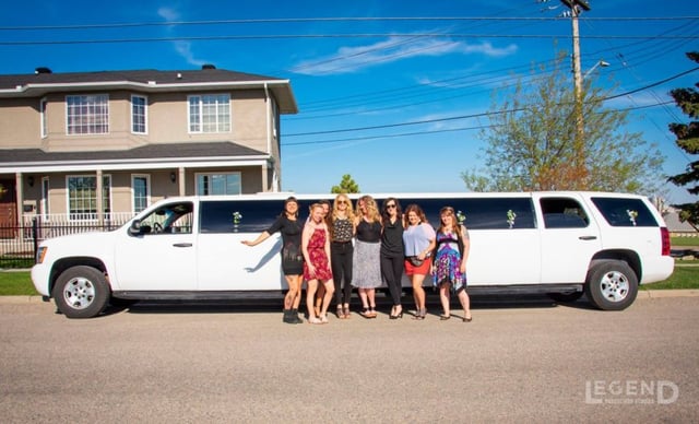 Group of ladies posing for photo in front of white Suburban limousine