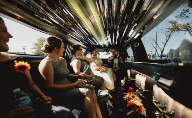 Wedding party celebrating inside of stretch limousine