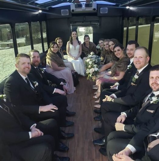 Wedding Party in tuxedos and gowns inside of a party bus