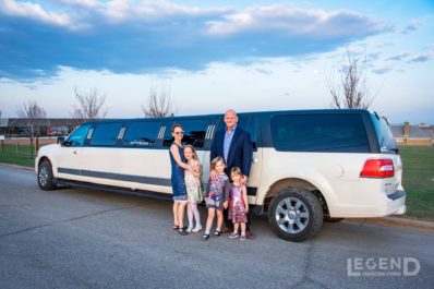 Family posing for photo in front of black and white Lincoln Navigator Stretch Limousine
