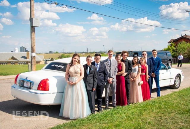 Group of high school graduates standing in front of a white Lincoln Stretch limousine