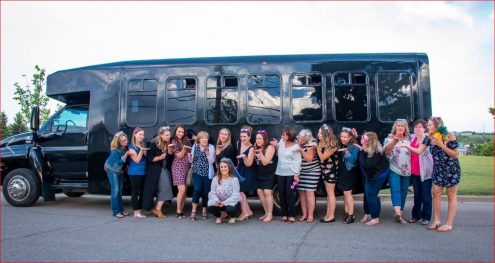 stagette photo with 16 ladies blowing kisses to bride to be in front ofblack party bus 