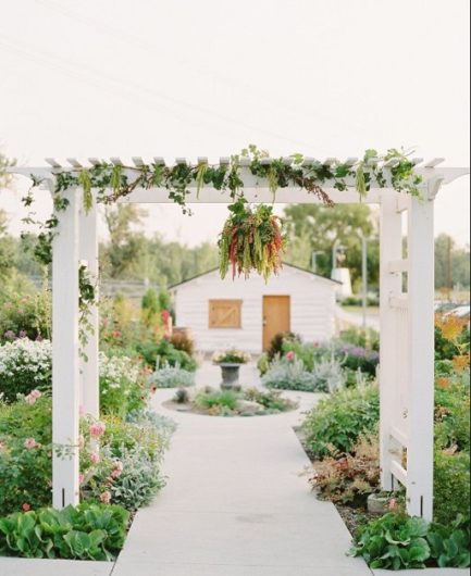 Deane House outdoor wedding ceremony area with white arches to walk under into a garden