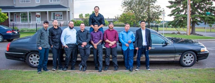 Stag celebration with 9 guys posing for photo in front of a black Lincoln Stretch Limousine