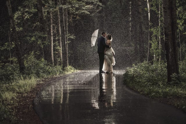 Bride and Groom standing in the rain with white umbrella