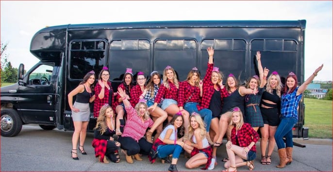Group of ladies all in red flannel shirts in front of a black party bus for bachelorette party