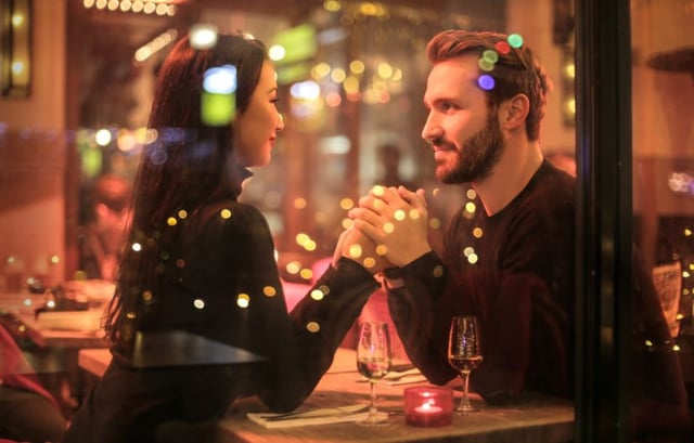 man and women holding hands on a date night setting in restaurant 