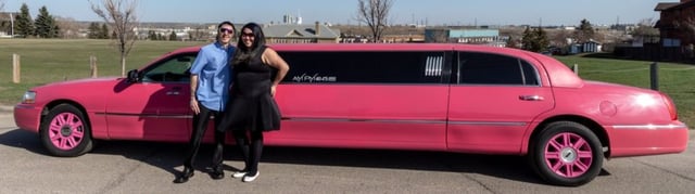 Couple standing in front of Pink Lincoln Stretch Limousine