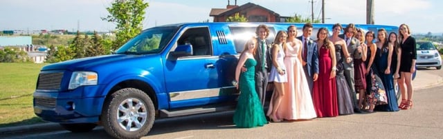 High School graduates dressed up, celebrating in front of Blue Expedition Limousine