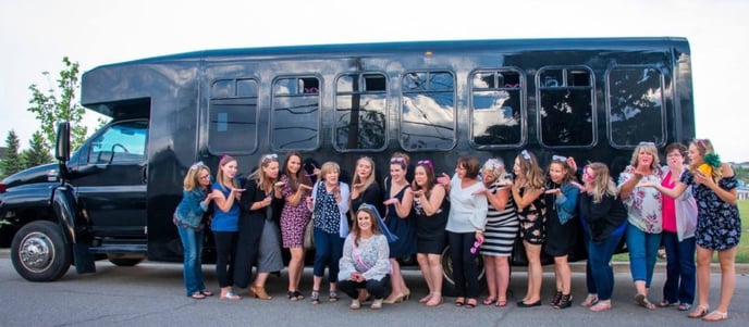 Group of ladies celebrating in front of black party bus