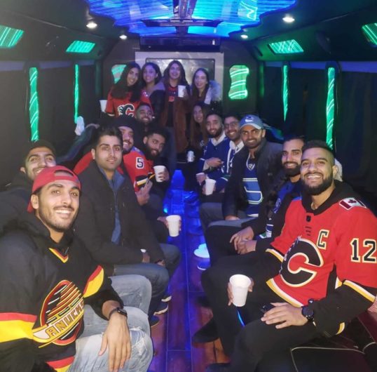 Group photo inside of party bus, everyone is wearing hockey jerseys 