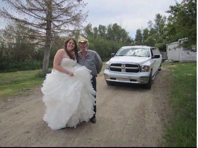 Bride in gown posing with driver in front of white limousine