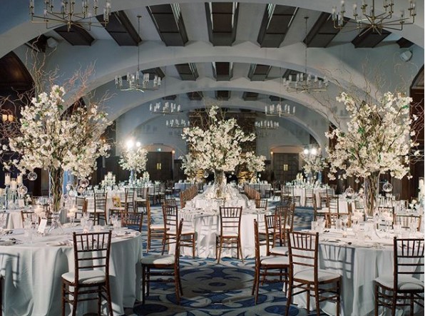 Photo of wedding reception hall with tables, chairs and centerpieces 