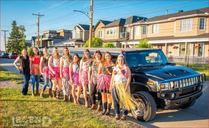 Group of ladies with Hawaiian skirts in front of black Hummer Limo