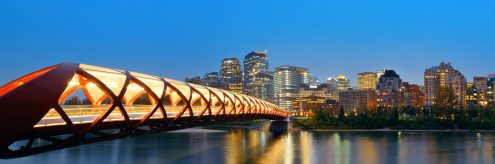Calgary Peace Bridge Lit up at dusk with dark blue sky and downtown Calgary in background