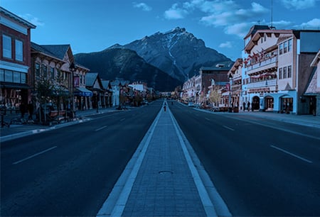 An empty Main Street in Banff Alberta with Rocky Mountians in the distance