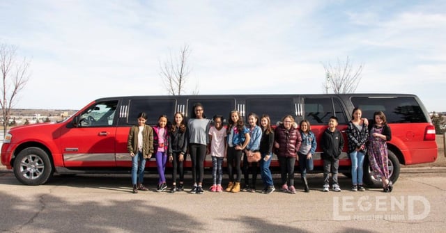 Group of kids celebrating birthday in front of red Expedition limousine
