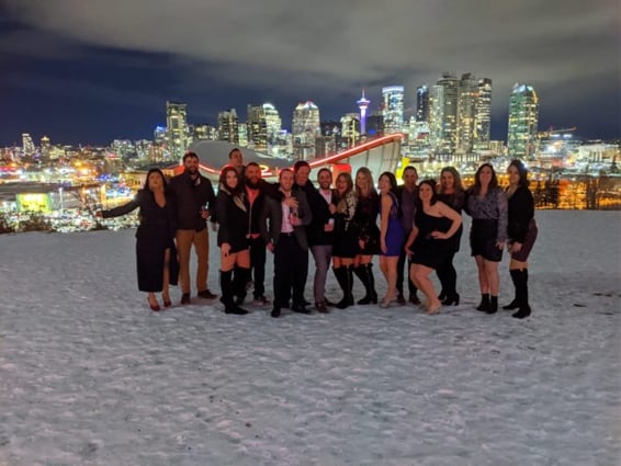 Group photo in winter on Scotsman's Hill with Saddledome and downtown Calgary skyline at night