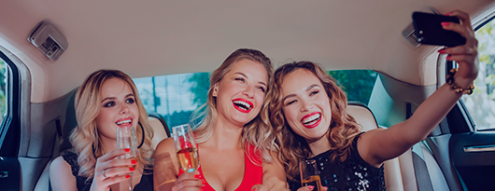 3 ladies taking a selfie in back of limo