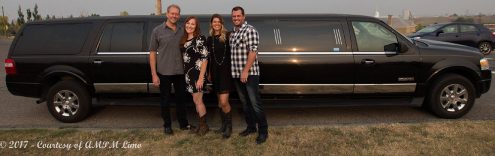 4 adults posing for photo in front of black Expedition Limousine