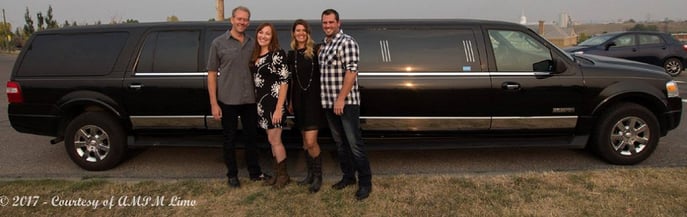 4 people posing for photo in front of black Expedition Limousine