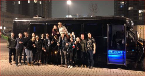 Group celebration photo in front of black party bus at night