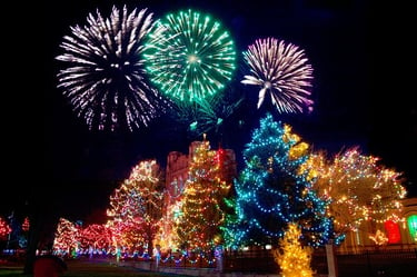 Fireworks going off above huge, fully lit Christmas Trees