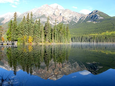 Photo of mountains and trees reflecting in a lake in Jasper, Alberta