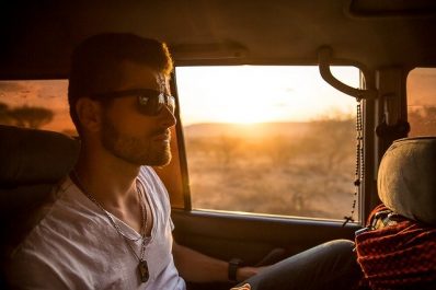 Man sitting in the back of a car with sunglasses on