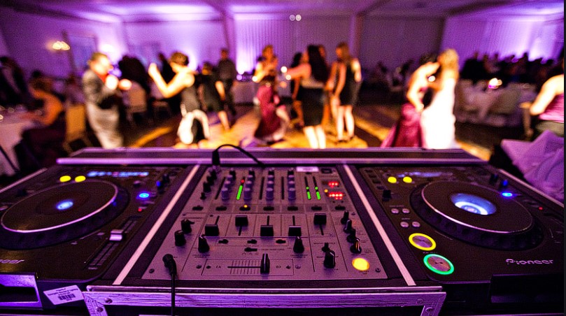 Close up picture of wedding DJ equipment with people dancing in the distance 