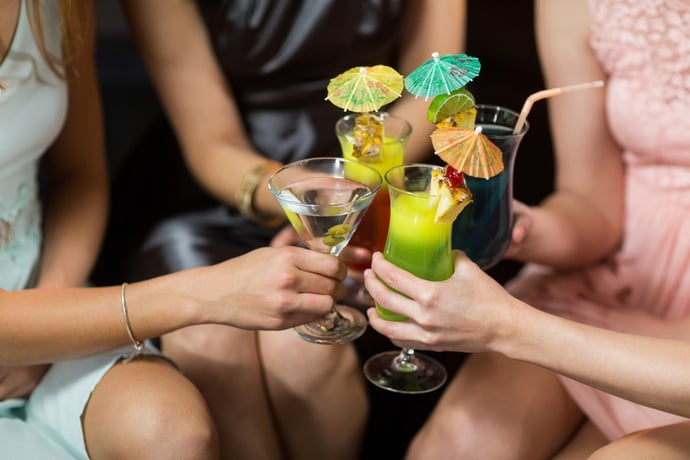 Mid section of female friends toasting glasses of cocktail in bar