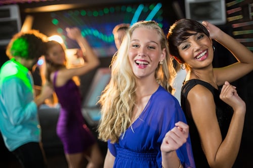Two beautiful women dancing on dance floor in bar